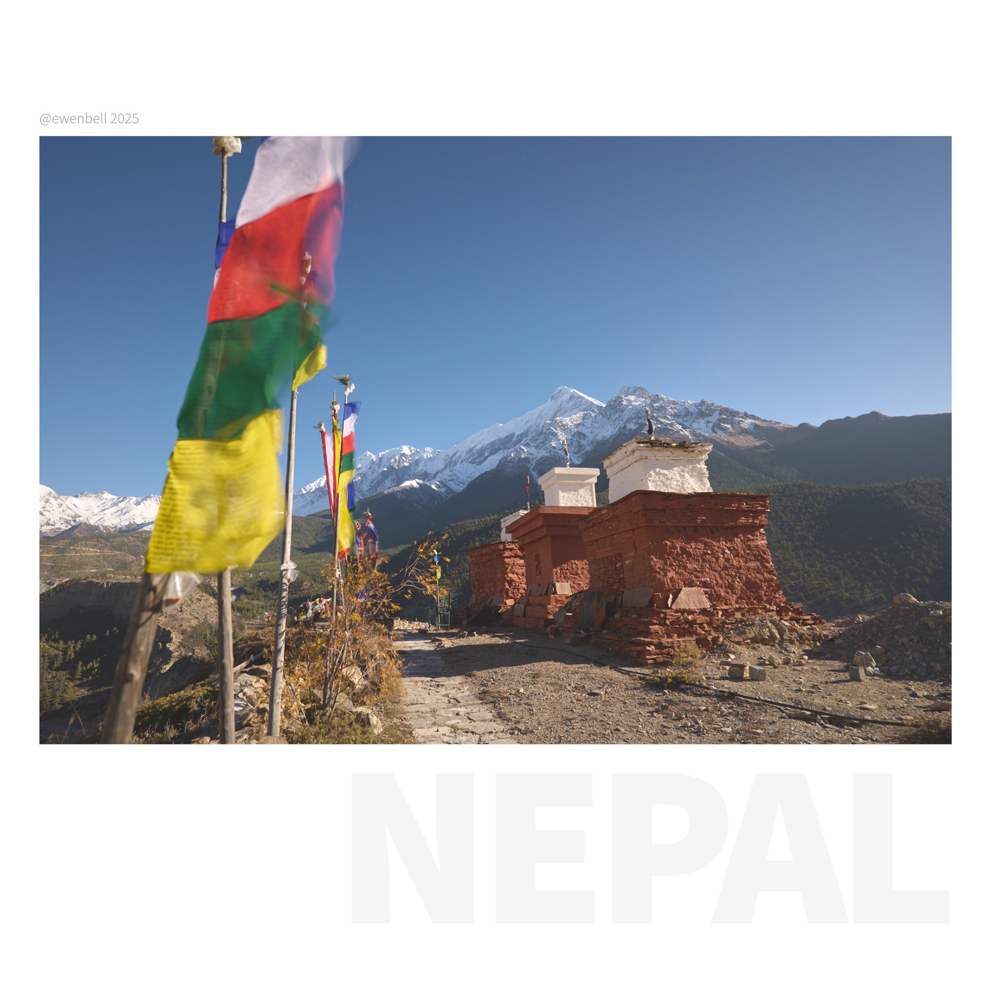 Prayer flags buffeted by the wind, next to a row of chorten with Nilgiri South in the background.