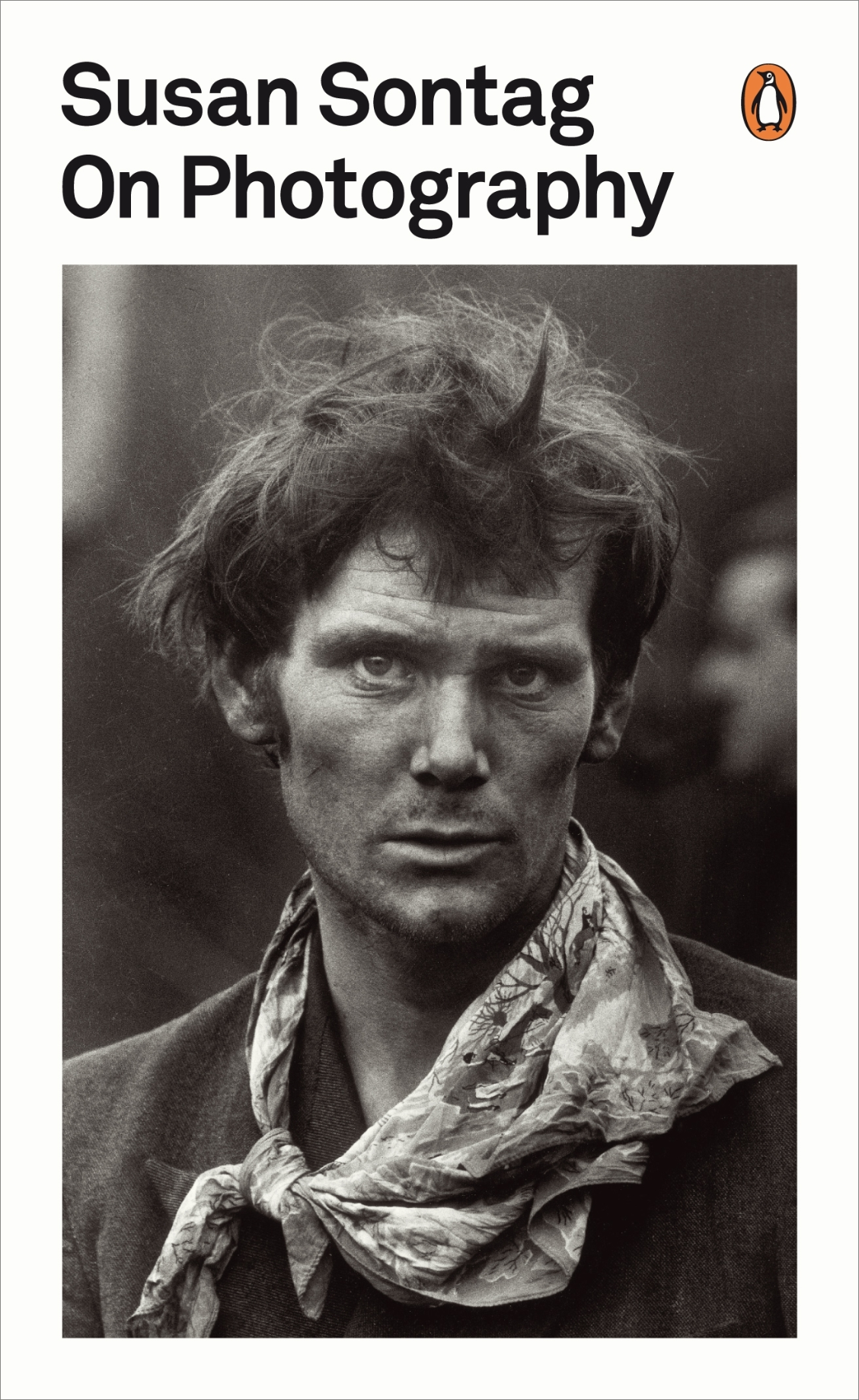 Cover of Susan Sontag's book "On Photography". Features a B+W image of a man with tussled hair and sporting a roughly tied scarf. The image at the time would pose a question about gender norms.